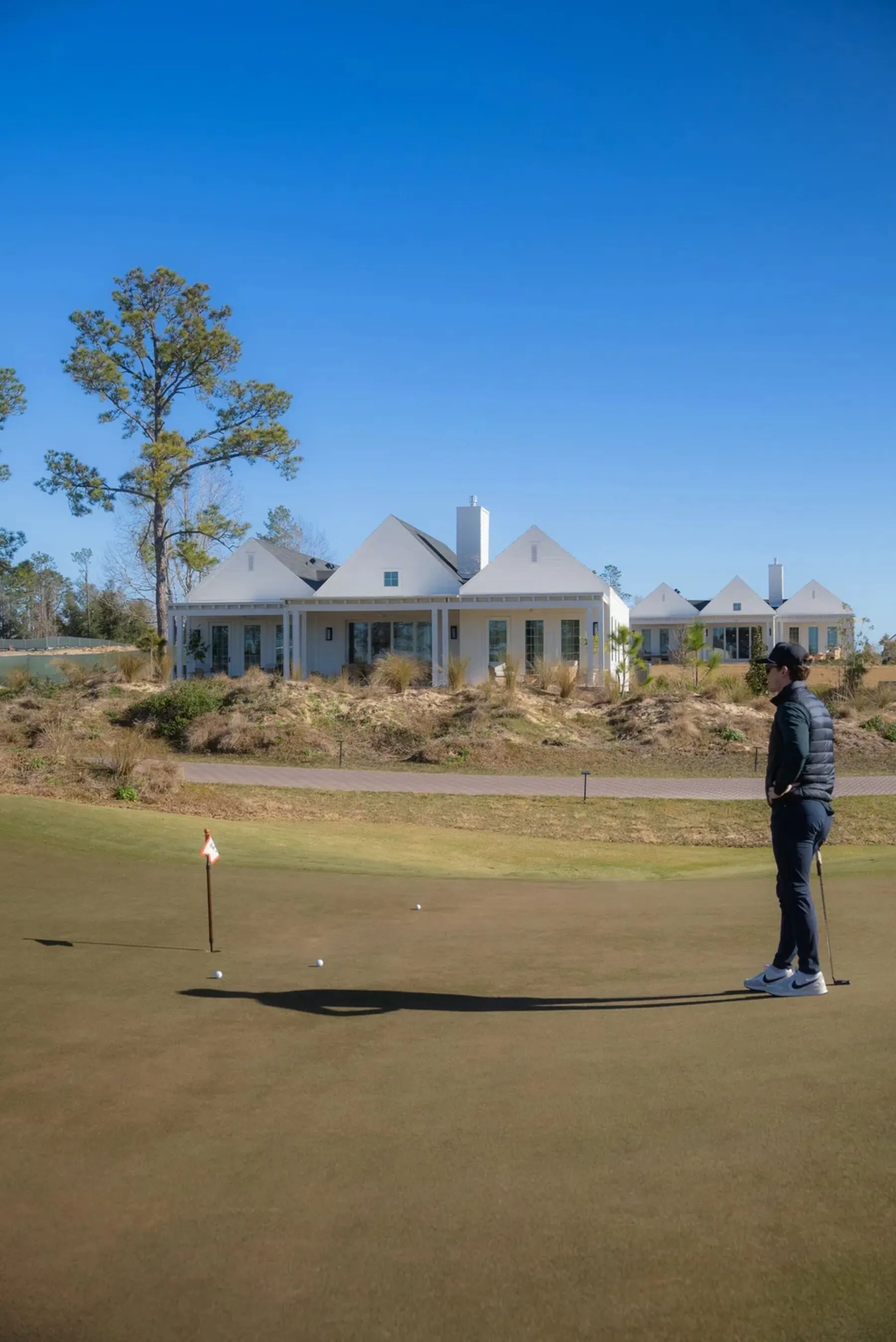 Golfer on the putting green with cottages behind