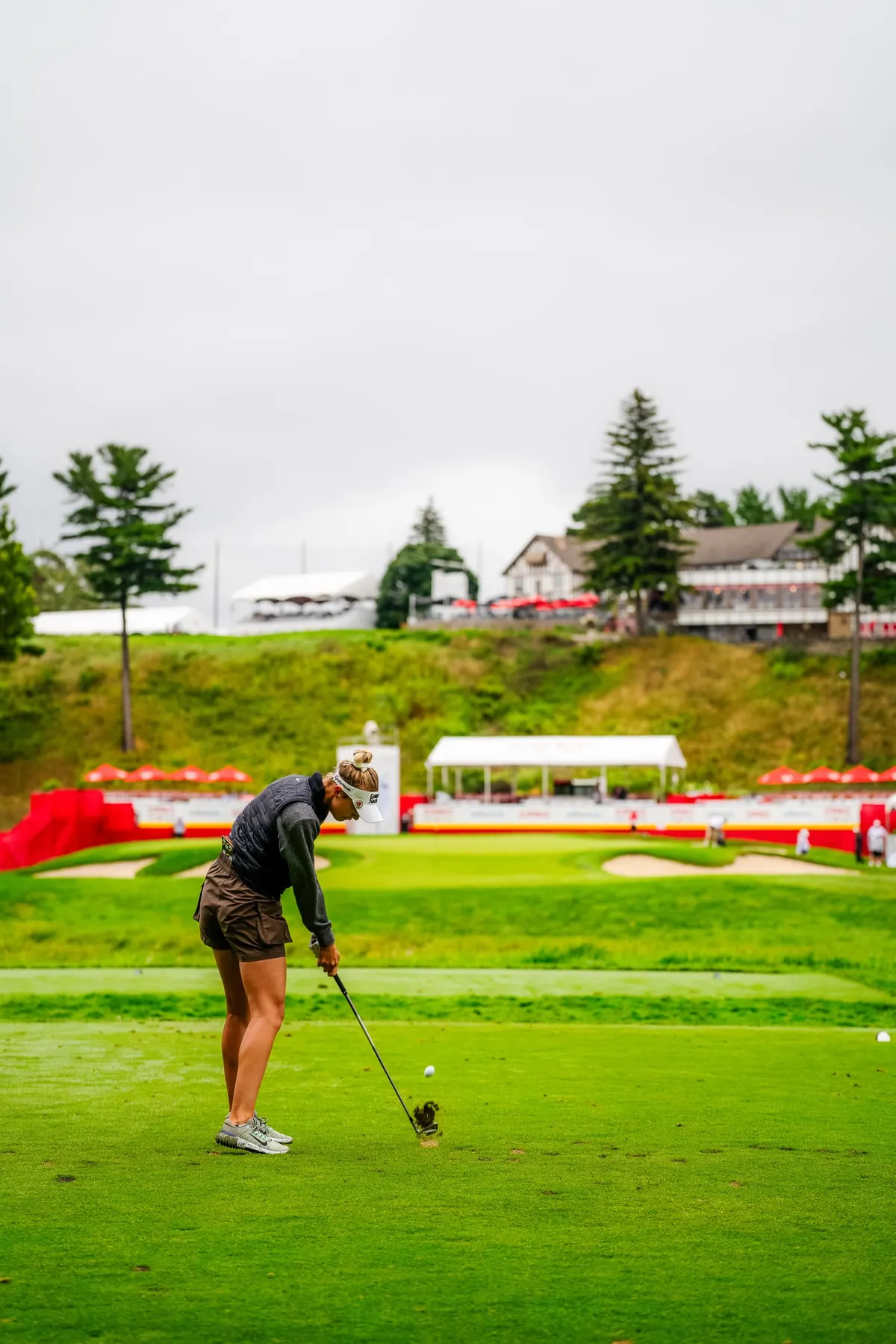 A player hits her approach with the clubhouse above the 18th green