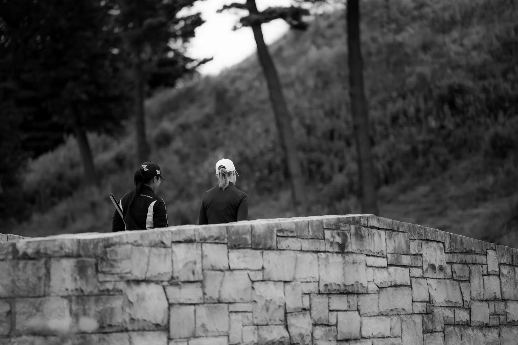Two players walking across a stone bridge, in black and white