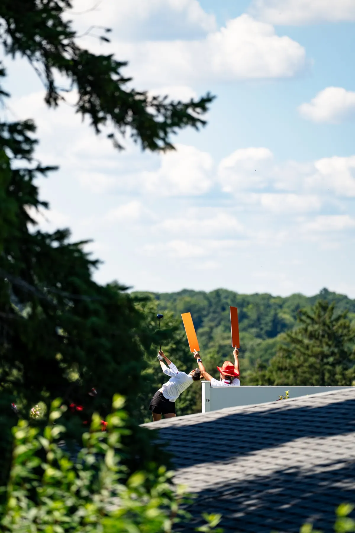 A marshal raises paddles as a player finishes her swing above a rooftop