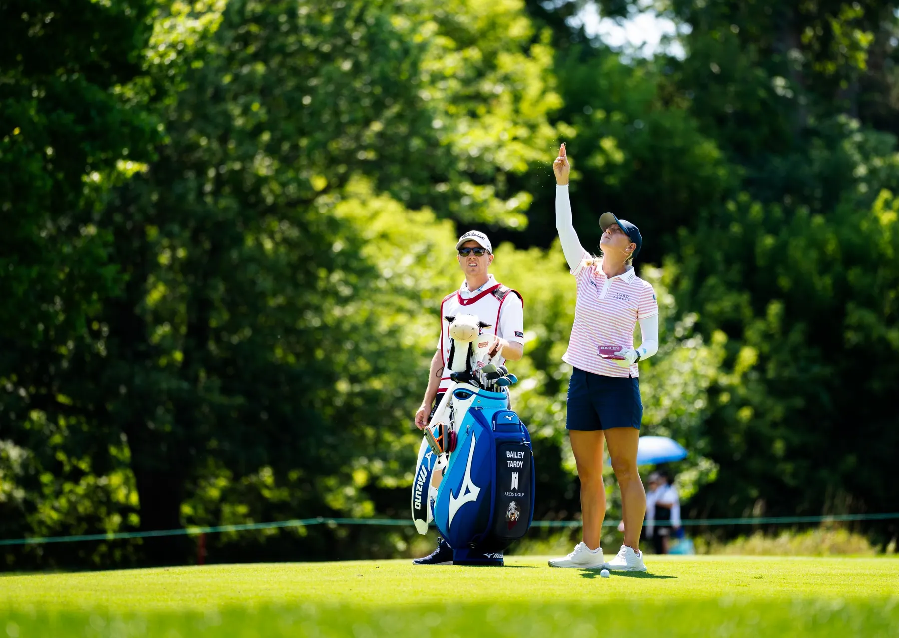 A player tosses grass to check the wind as her caddie looks on