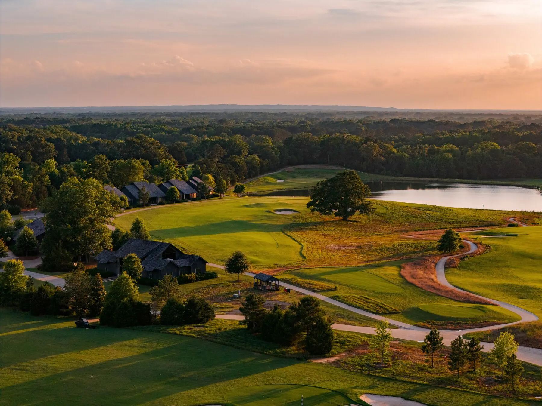 Fairway with cottages and lake beyond at Mossy Oak at golden hour