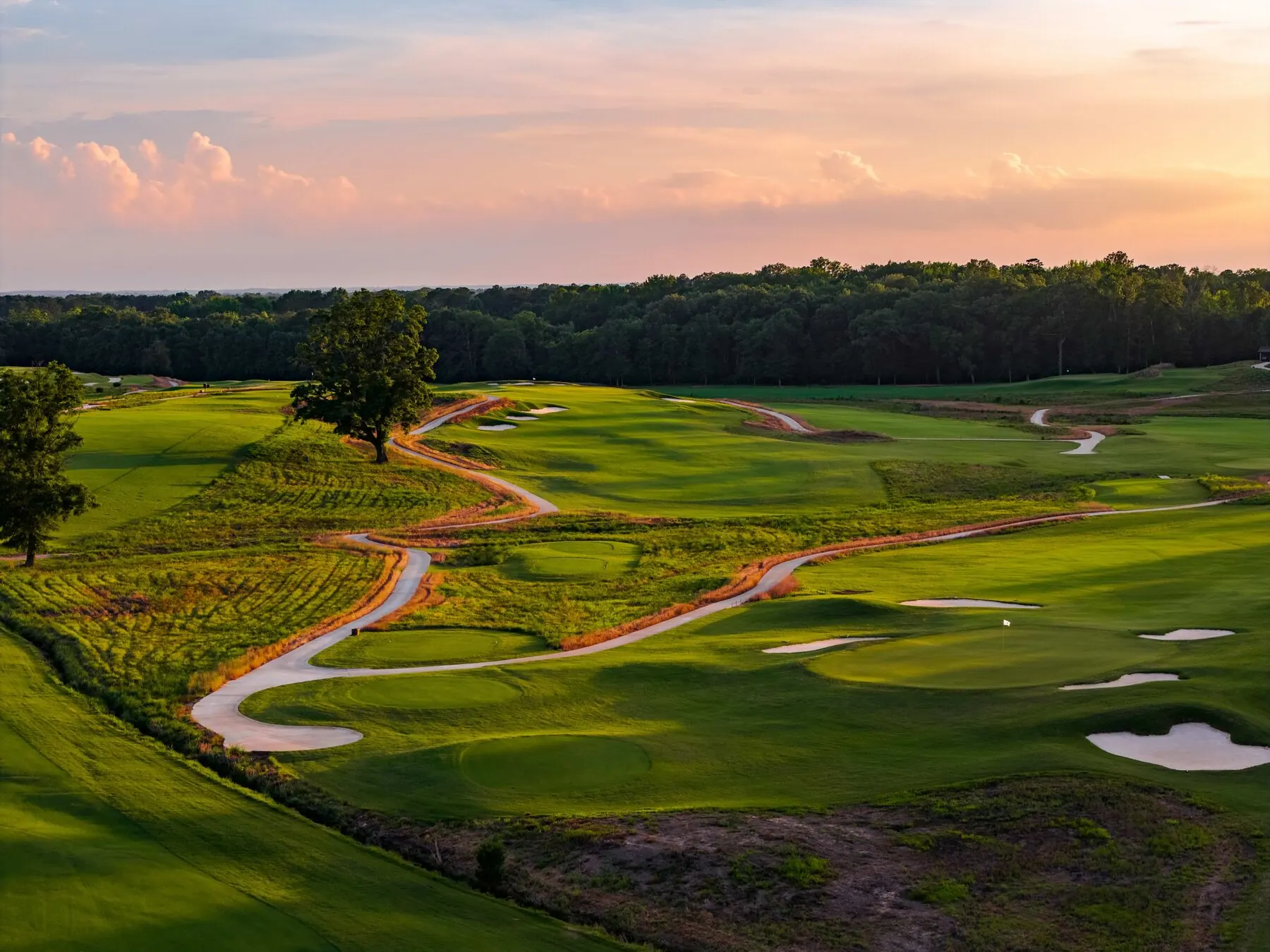 Cart path winding through bunkers at Mossy Oak at sunset