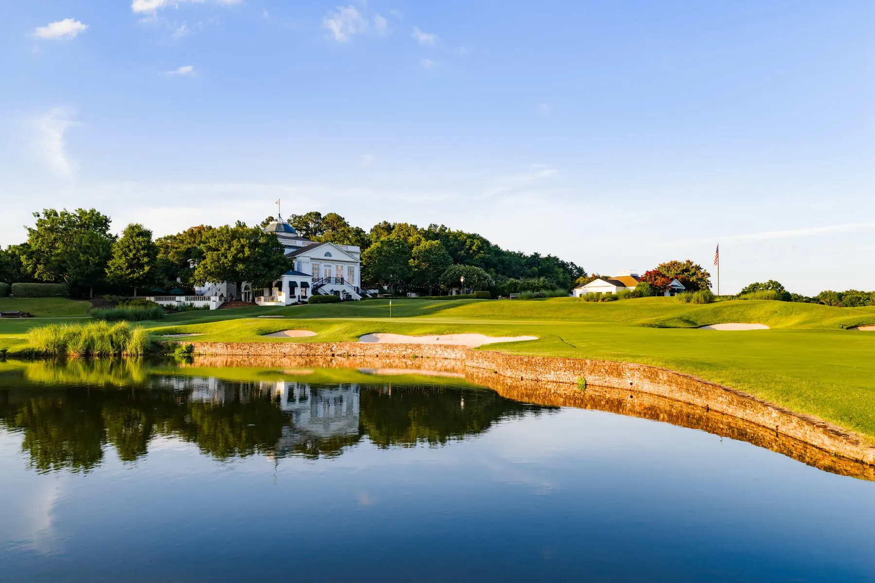 Old Waverly clubhouse across the lake beside a stone-walled bunker