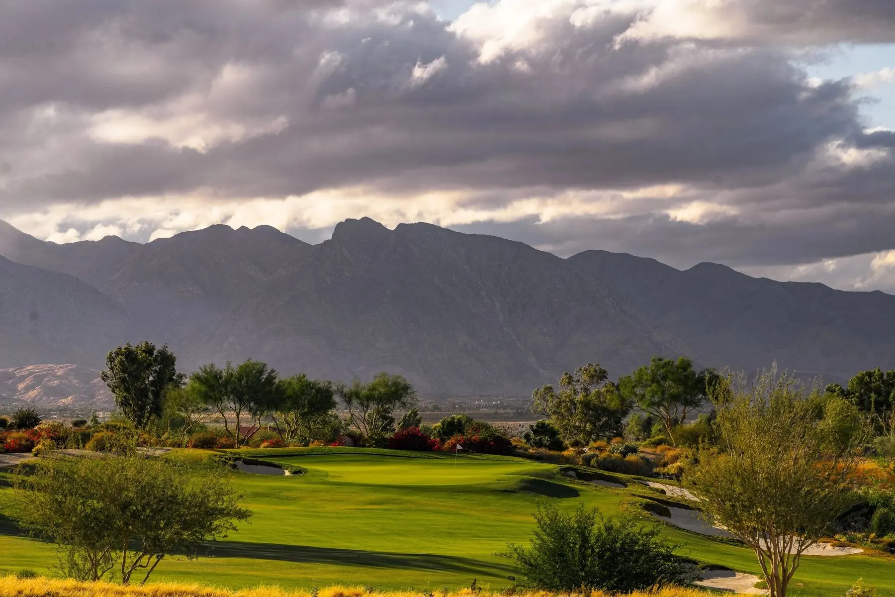 Green and bunker with mountains beyond at Rams Hill